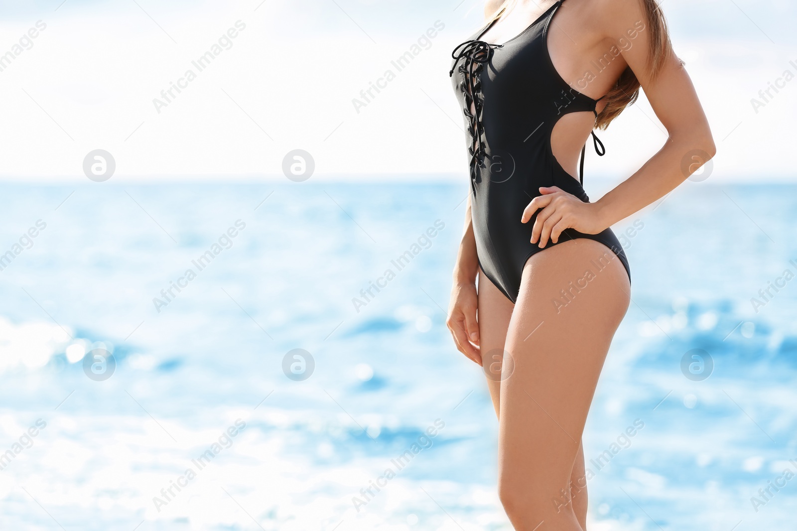 Photo of Attractive young woman in beautiful one-piece swimsuit on beach, closeup