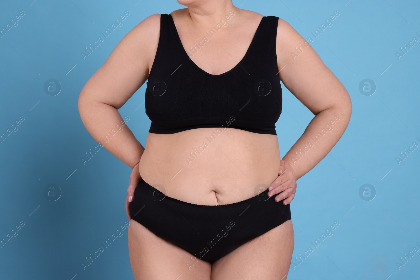 Photo of Overweight woman in underwear on light blue background, closeup