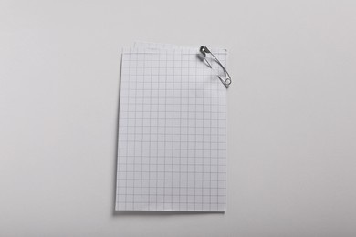 Photo of Sheets of paper attached with safety pin on white background, top view