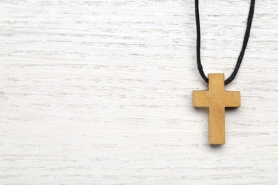 Photo of Wooden Christian cross on white table, top view. Space for text