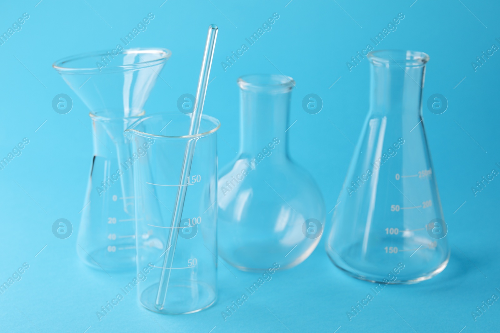 Photo of Different laboratory glassware on light blue background