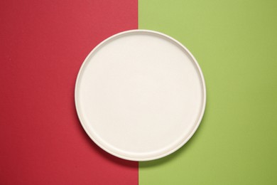 Photo of One ceramic plate on color background, top view