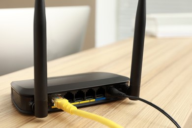 Photo of Modern wi-fi router on wooden counter indoors, closeup