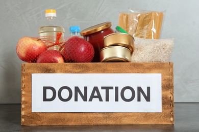 Photo of Donation box with food on table against light background