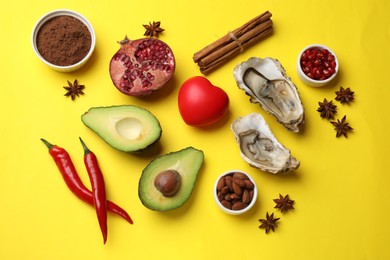 Photo of Natural aphrodisiac. Different food products and red decorative heart on yellow background, flat lay