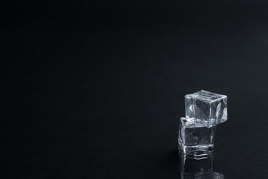 Photo of Crystal clear ice cubes on black background. Space for text