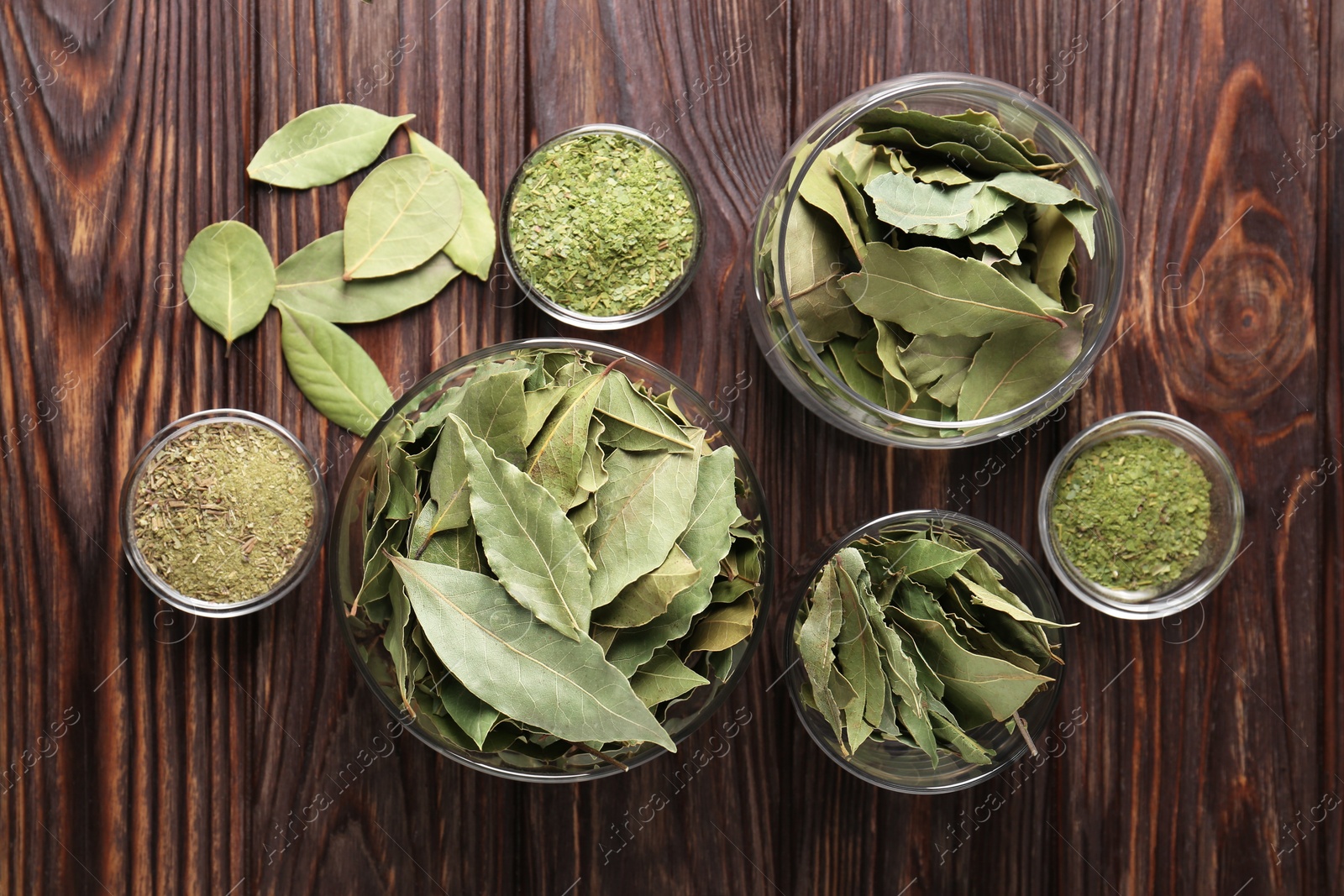 Photo of Whole and ground bay leaves on wooden table, flat lay