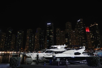 DUBAI, UNITED ARAB EMIRATES - NOVEMBER 03, 2018: Night cityscape with luxury yachts moored at pier