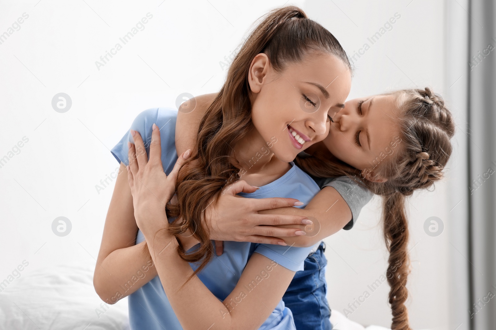 Photo of Cute daughter kissing and hugging her mom indoors