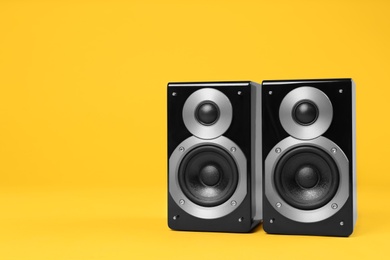 Photo of Modern powerful audio speakers on yellow background, space for text