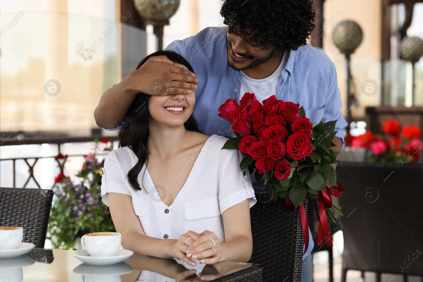 Photo of International dating. Handsome man presenting roses to his girlfriend in restaurant