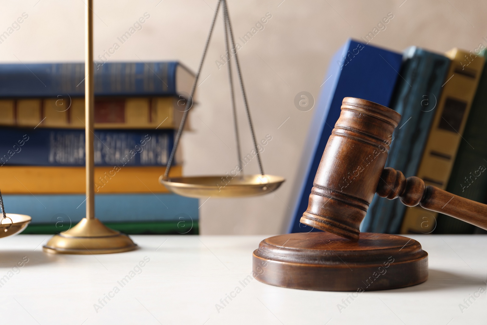 Photo of Wooden gavel with scales of justice and books on table against color background. Law concept