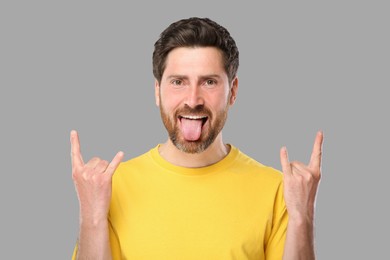 Photo of Man showing his tongue and rock gesture on gray background
