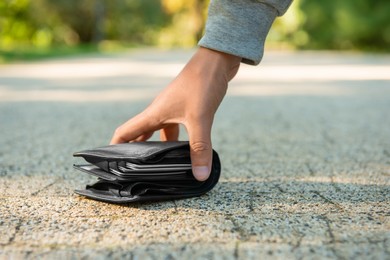 Photo of Man picking lost wallet from ground outdoors, closeup. Space for text