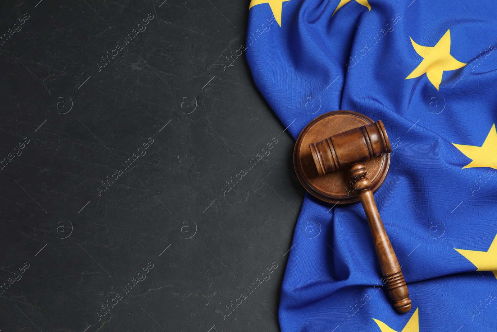 Photo of Wooden judge's gavel and flag of European Union on black table, flat lay. Space for text