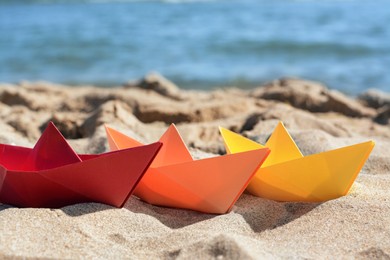 Three paper boats near sea on sunny day, closeup