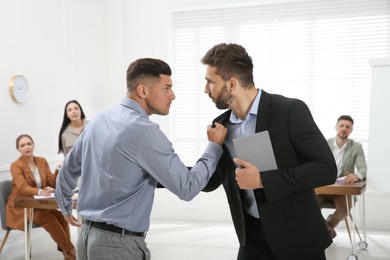 Photo of Emotional colleagues fighting in office. Workplace conflict