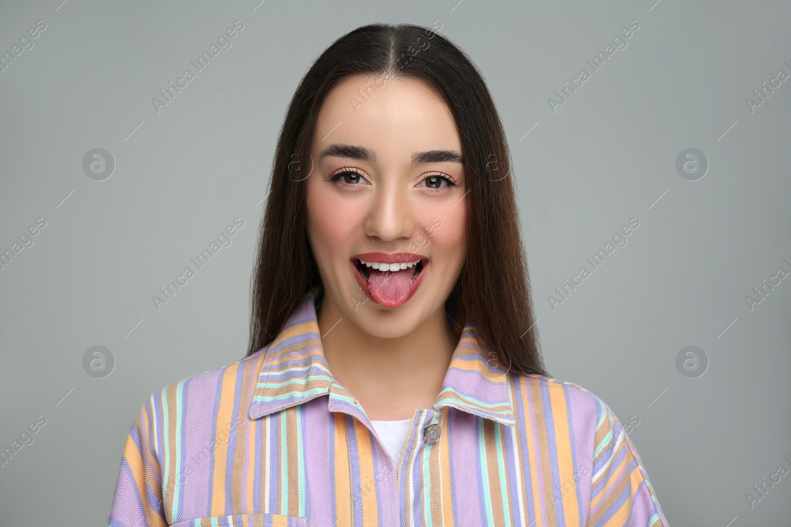 Photo of Happy woman showing her tongue on gray background