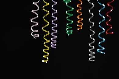 Photo of Many colorful serpentine streamers on black background