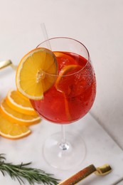 Glass of tasty Aperol spritz cocktail with orange slices on white table, closeup