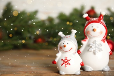 Photo of Funny little snowmen on wooden table, space for text