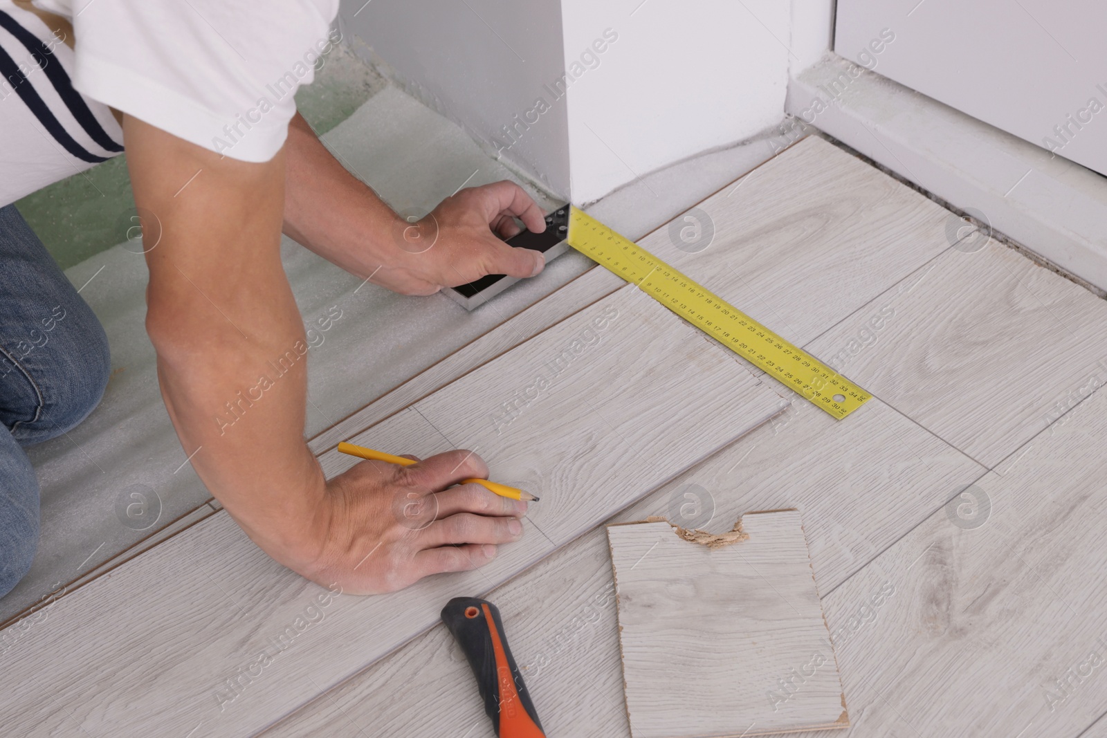 Photo of Man using measuring tape during installation of laminate flooring, closeup