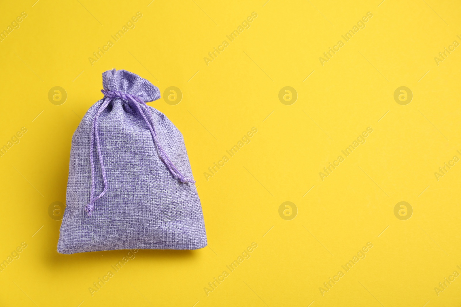 Photo of Violet burlap bag on yellow background, top view. Space for text