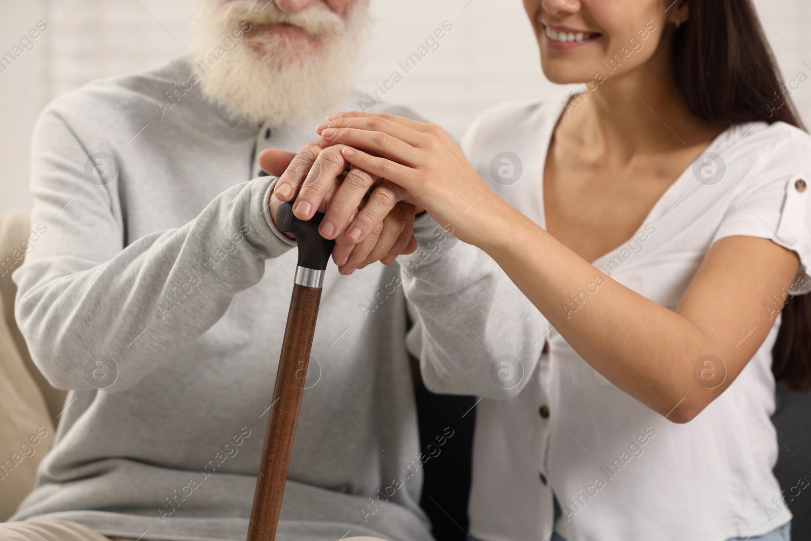 Photo of Senior man with walking cane and young woman indoors, closeup