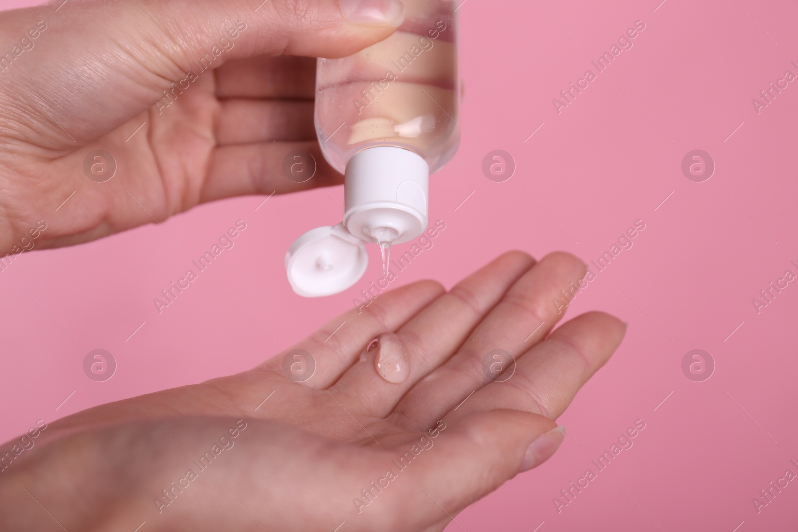 Photo of Woman applying antiseptic gel on pink background, closeup