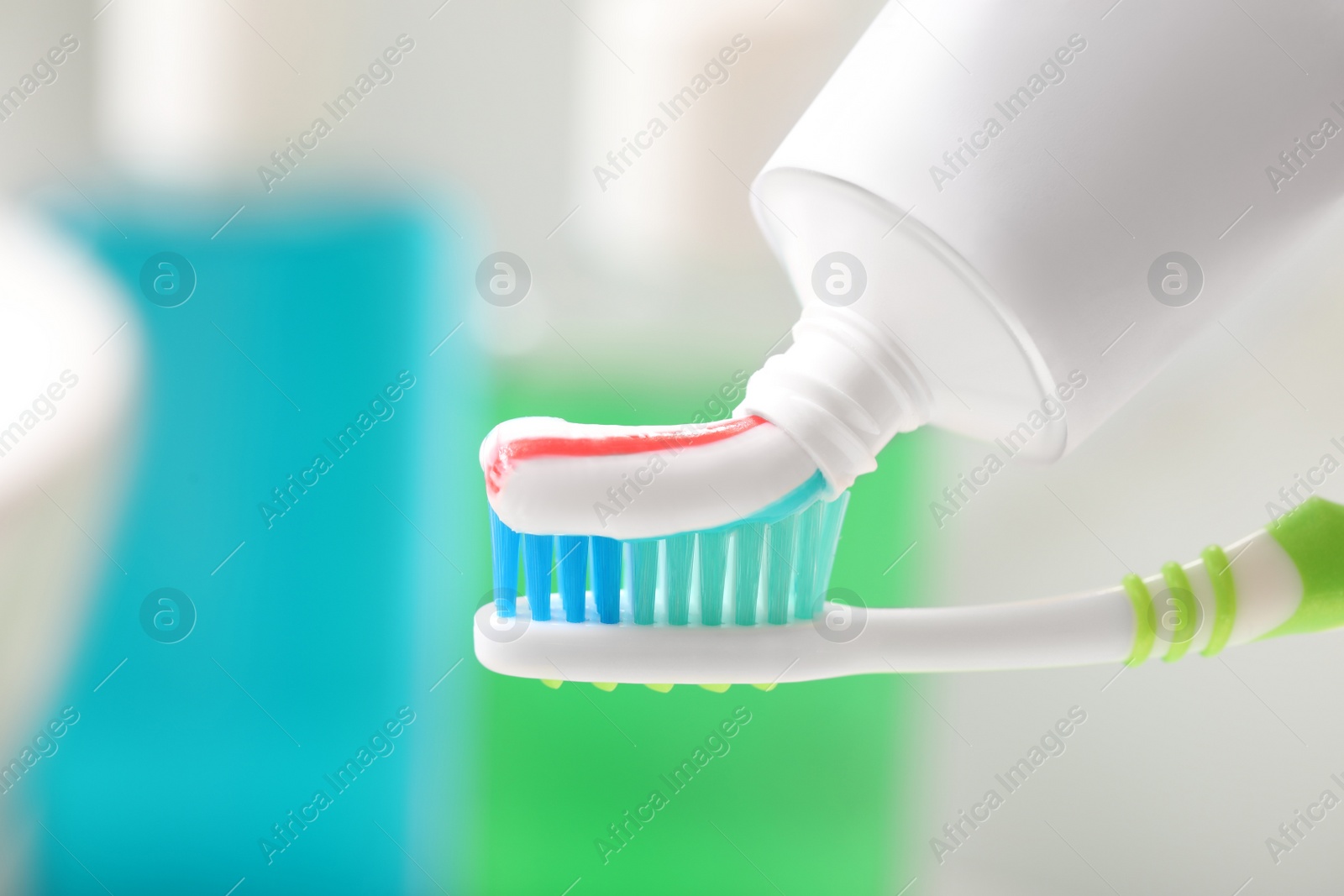 Photo of Applying toothpaste on brush against blurred background, closeup