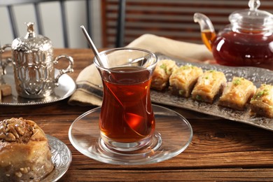 Photo of Turkish tea and sweets served in vintage tea set on wooden table