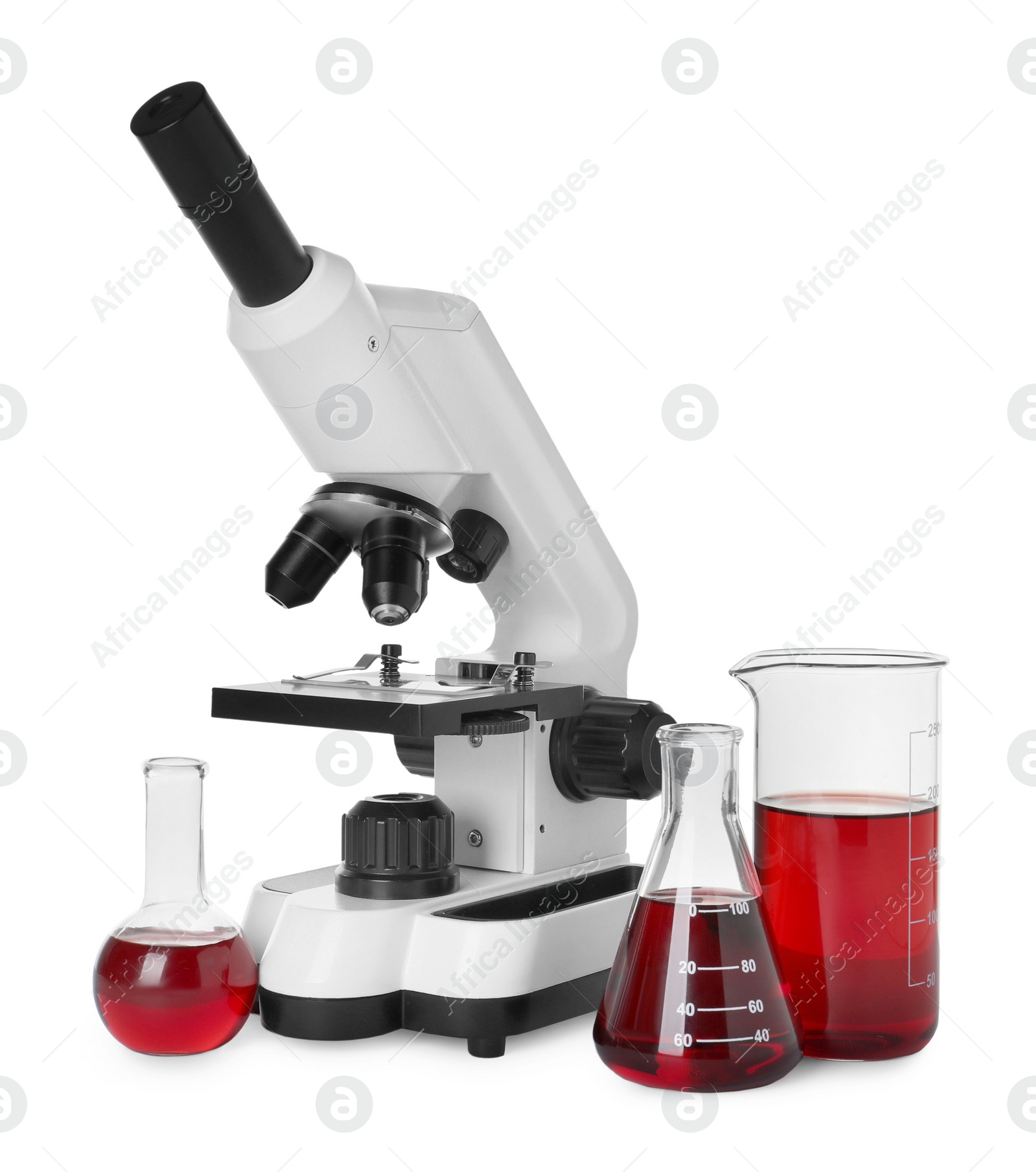 Photo of Laboratory glassware with red liquid and microscope isolated on white