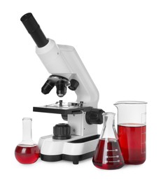 Photo of Laboratory glassware with red liquid and microscope isolated on white