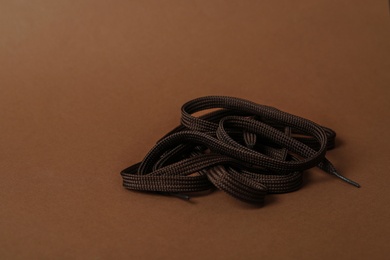 Photo of Dark shoe lace on brown background. Space for text