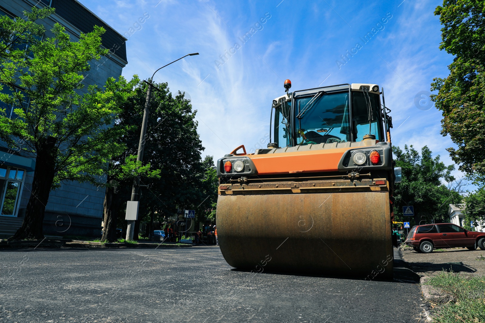 Photo of Roller working on city street, low angle view. Road repairing