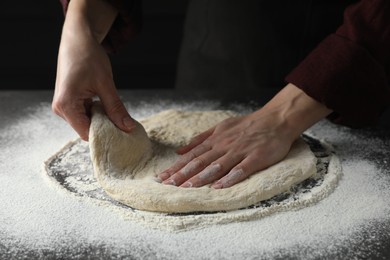 Woman kneading pizza dough at table, closeup