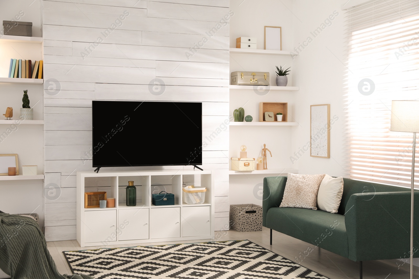 Photo of Cozy room interior with stylish furniture, decor and modern TV set