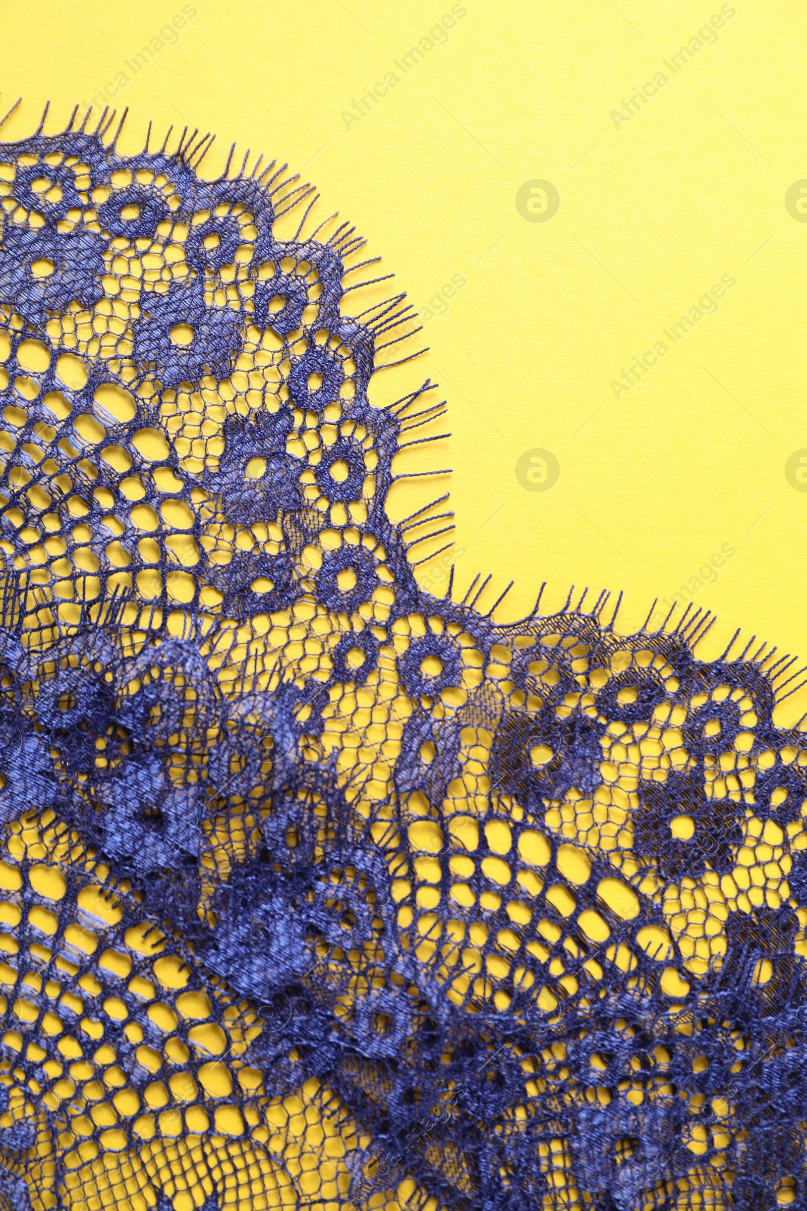 Photo of Blue lace on yellow background, top view