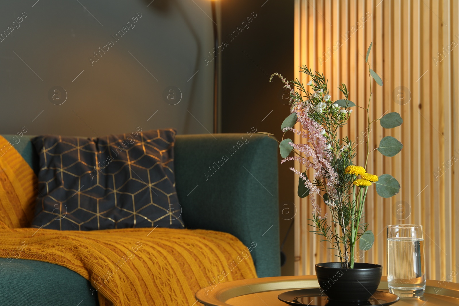 Photo of Stylish ikebana with beautiful flowers and green branches carrying cozy atmosphere at home