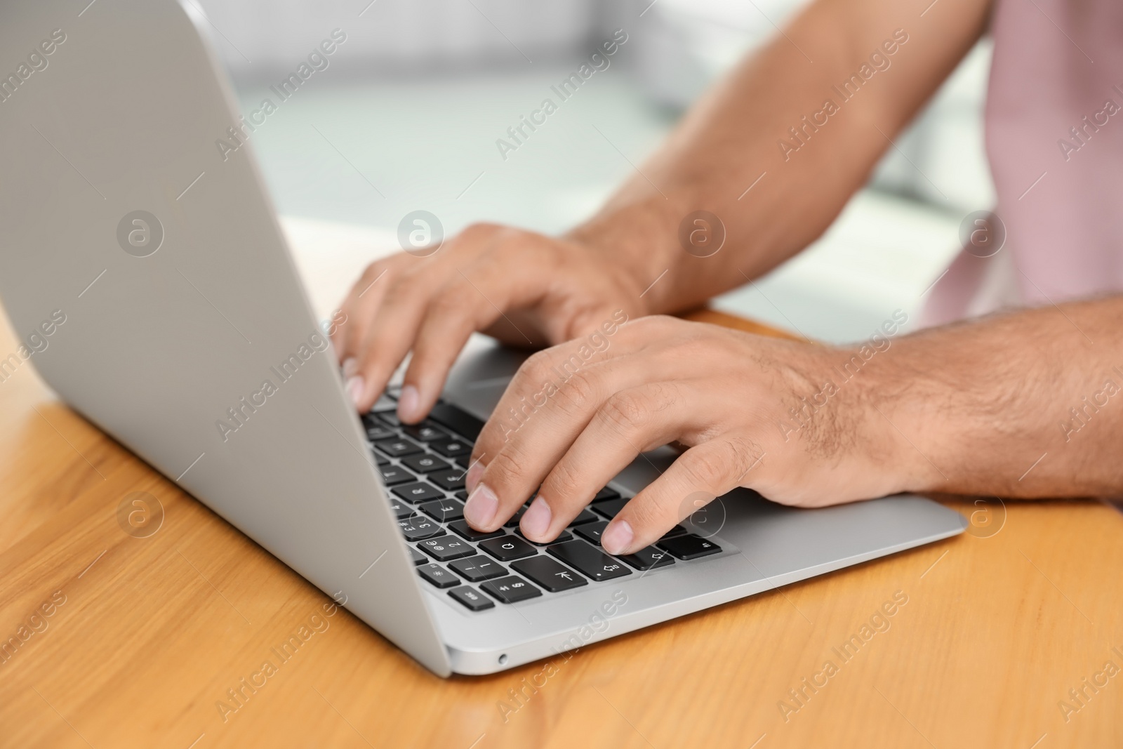 Photo of Man using laptop for search at wooden table indoors, closeup