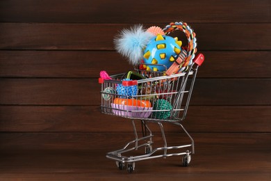 Photo of Shopping cart with different pet shop goods on wooden background