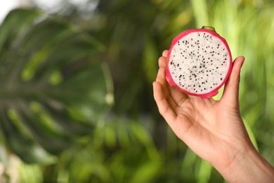 Woman holding fresh cut dragon fruit (pitahaya) on blurred background, closeup. Space for text