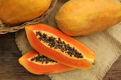 Photo of Tasty whole and cut papaya fruits on wooden table, flat lay