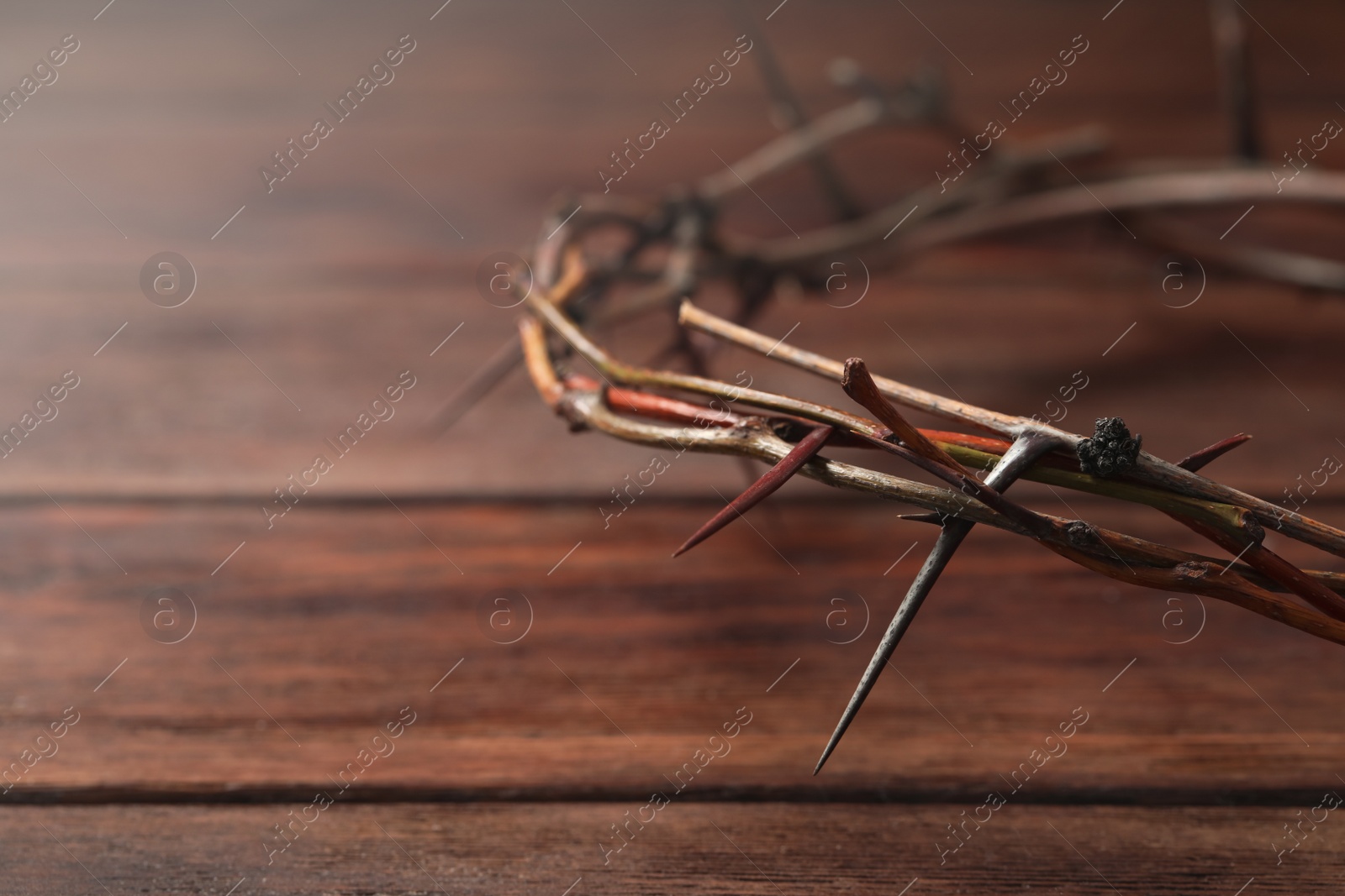 Photo of Crown of thorns on wooden table, closeup with space for text. Easter attribute