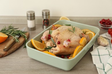 Photo of Chicken with orange slices in baking pan on wooden table