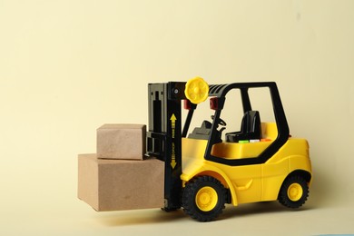 Toy forklift with boxes on beige background. Logistics and wholesale concept