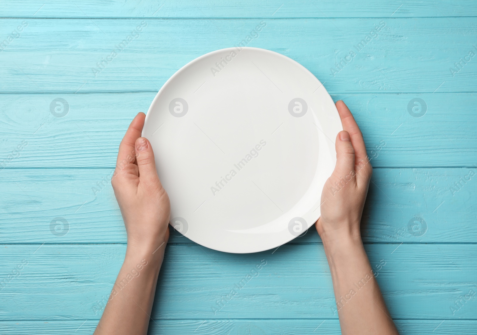 Photo of Woman with empty plate at wooden table, top view