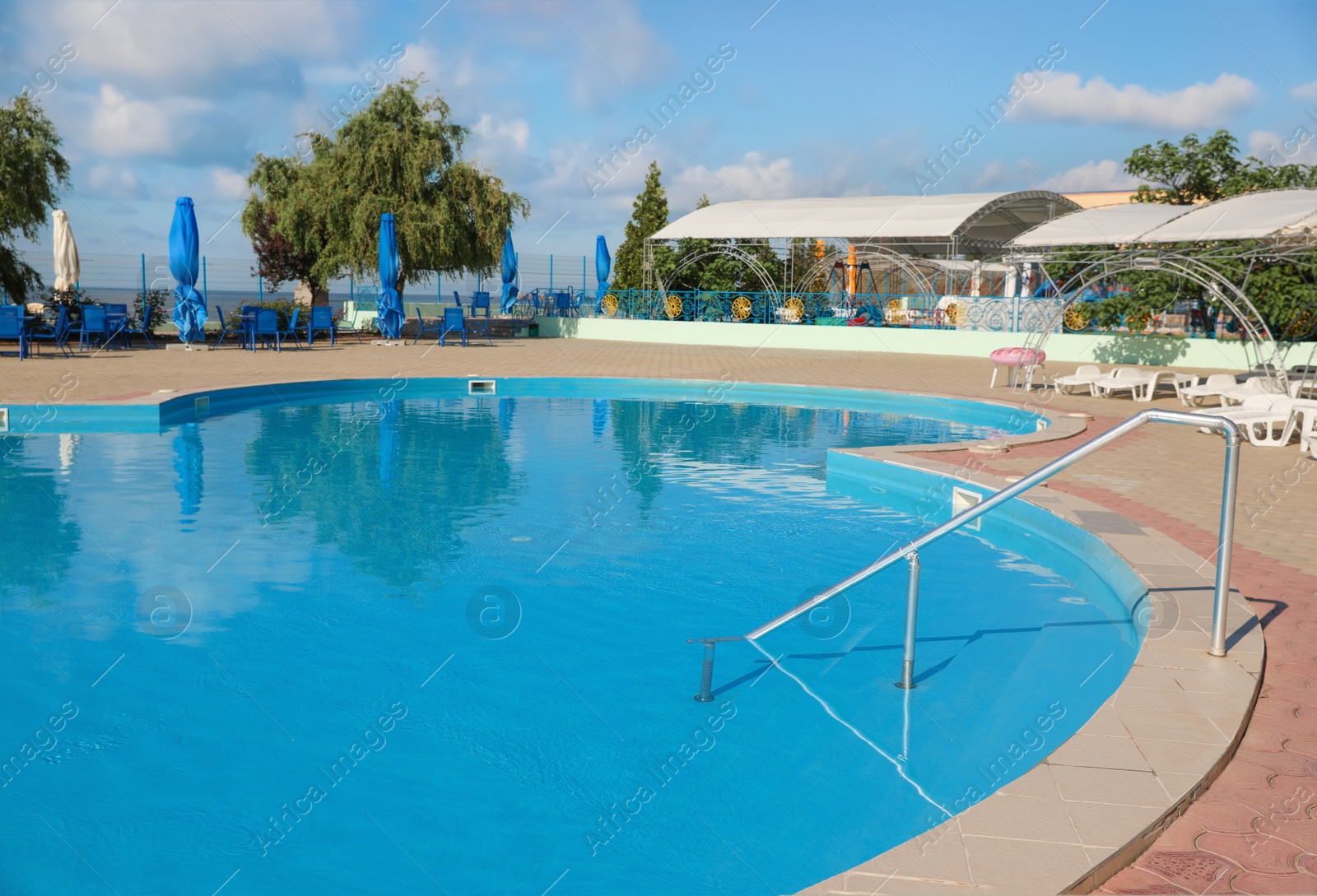 Photo of Outdoor swimming pool with clear water on sunny day. Summer vacation