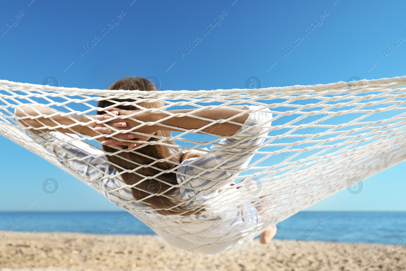 Photo of Young woman relaxing in hammock on beach