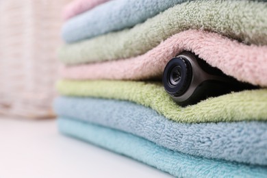 Photo of Camera hidden between folded towels indoors, closeup. Space for text